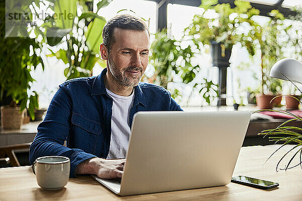 Geschäftsmann surft mit Laptop im Loft-Büro im Internet