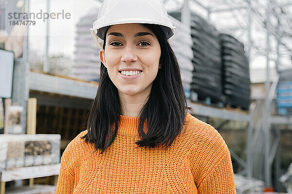 Lächelnde Frau mit Schutzhelm auf der Baustelle