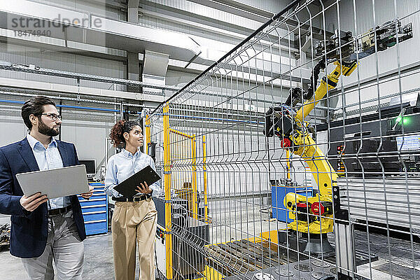 Geschäftskollegen untersuchen Roboterarm in der Fabrik