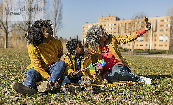 Glückliche Seniorin macht Selfie mit Tochter und Enkel im Park