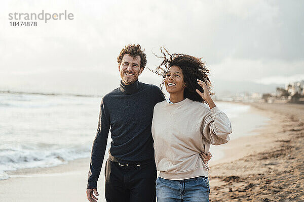 Glücklicher Mann und Frau  die gemeinsam am Strand spazieren gehen