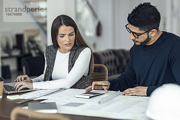 Architekten diskutieren am Schreibtisch über Dokumente und berechnen Finanzen