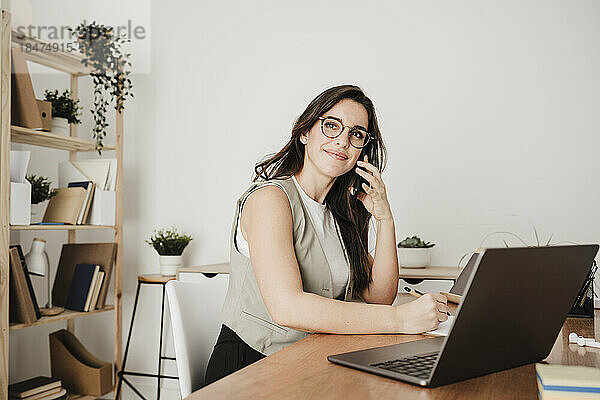 Lächelnde Geschäftsfrau  die im Büro über einen Laptop spricht