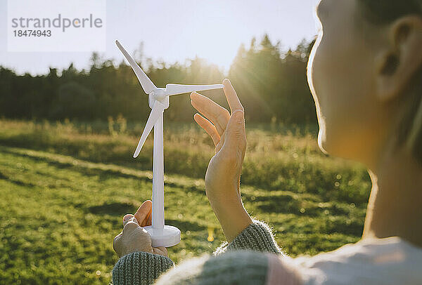 Frau berührt Windturbinenmodell an sonnigem Tag