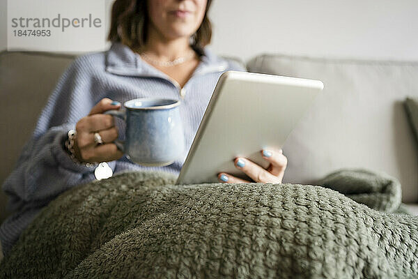 Frau benutzt Tablet-PC auf Sofa zu Hause