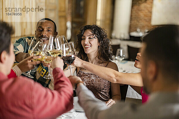 Glückliche gemischtrassige Freunde  die im Restaurant Weingläser anstoßen