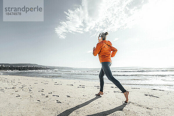 Reife Frau joggt am Strand