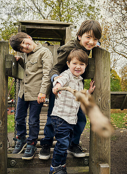 Fröhlicher Junge spielt mit Pflanzenstäbchen von Brüdern im Park