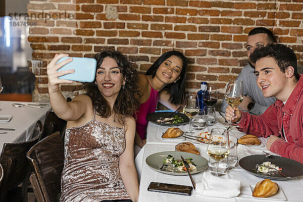 Glückliche Frau macht Selfie mit Freunden im Restaurant