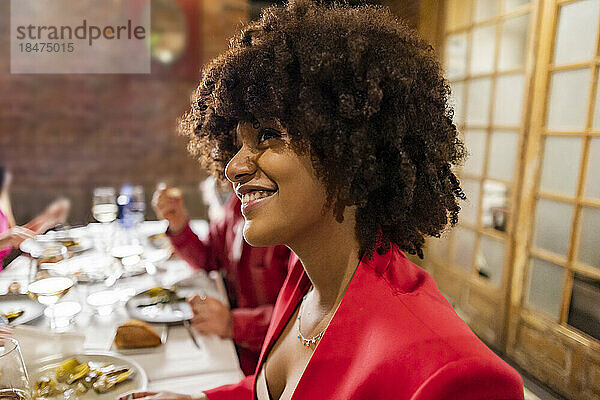 Glückliche Frau mit Afro-Frisur beim Abendessen im Restaurant