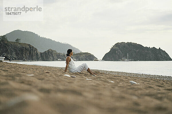Frau sitzt auf Sand am Strand