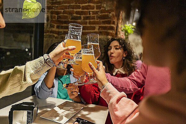 Freunde stoßen am Tisch im Restaurant mit Biergläsern an