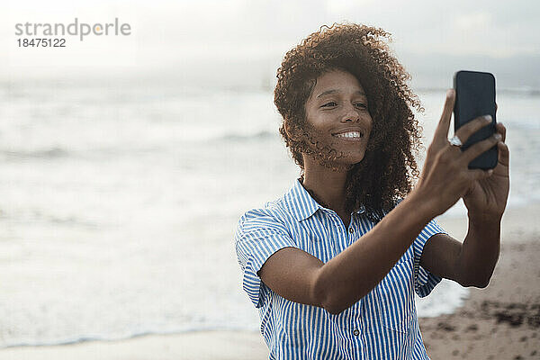 Glückliche junge Frau  die am Strand ein Selfie mit dem Smartphone macht