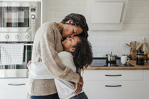 Mutter küsst Tochter zu Hause in der Küche