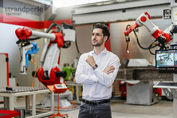Nachdenklicher Ingenieur steht in der Roboterfabrik