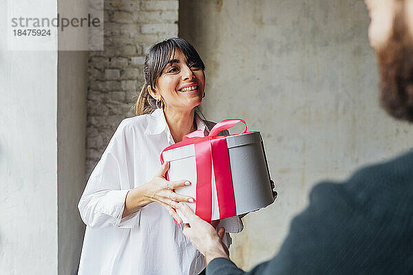 Happy woman giving gift to man at home