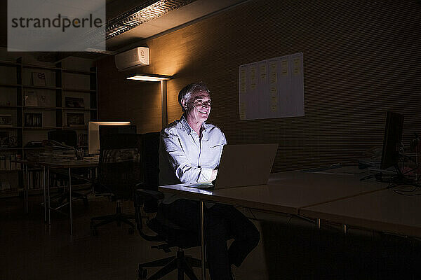 Happy senior businessman working late at workplace