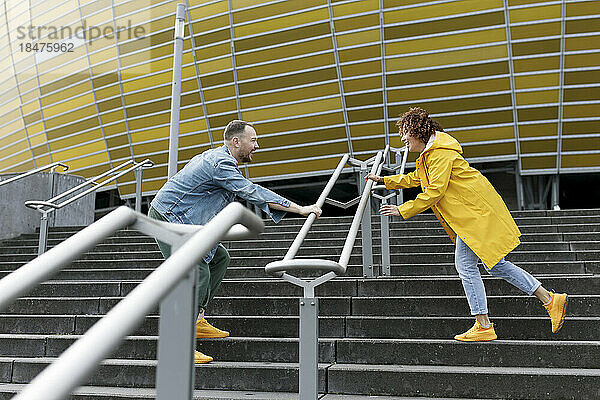 Happy couple playing on staircase outside stadium
