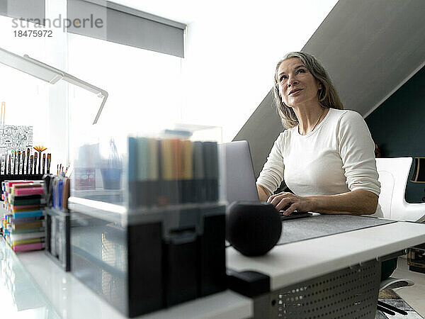 Nachdenkliche Geschäftsfrau sitzt am Schreibtisch im Büro