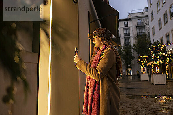 Lächelnde junge Frau  die mit dem Smartphone fotografiert