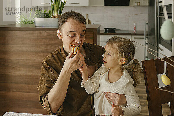 Tochter füttert Vater zu Hause mit Pfannkuchen