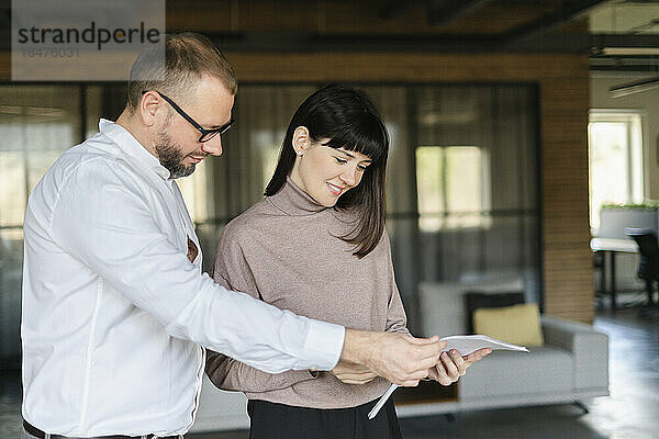 Geschäftsmann und Frau diskutieren Dokument im Büro