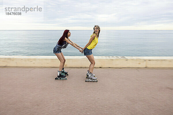 Freunde beim Rollschuhlaufen und Spaß an der Promenade am Meer