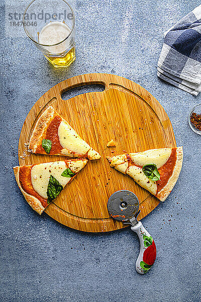 Slices of pizza with cutter and beer kept on table