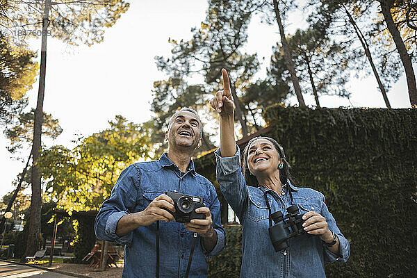 Neugieriges reifes Paar mit Kamera und Fernglas im Freien