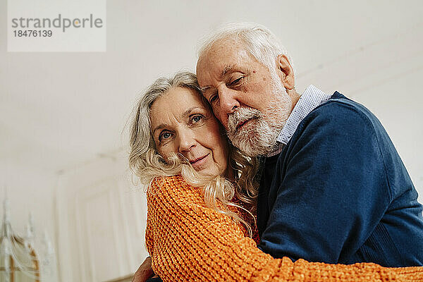 Senior man and woman hugging each other at home