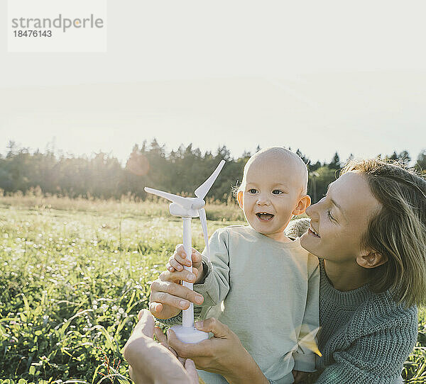 Glückliche Mutter spielt mit Sohn  der ein Windturbinenmodell hält