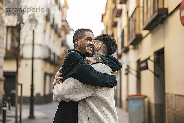 Glückliches schwules Paar  das sich vor dem Gebäude umarmt