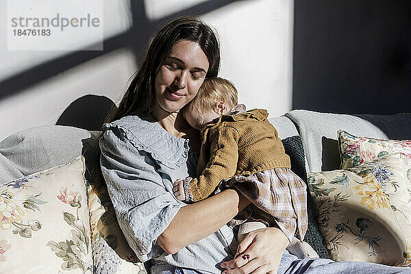 Mutter mit kleinem Mädchen entspannt sich zu Hause auf dem Sofa