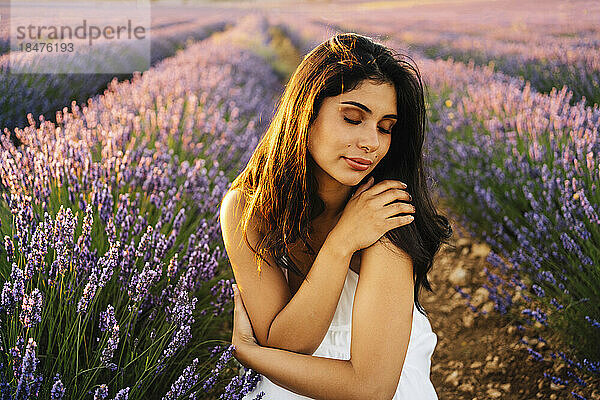 Junge Frau umarmt sich im Lavendelfeld