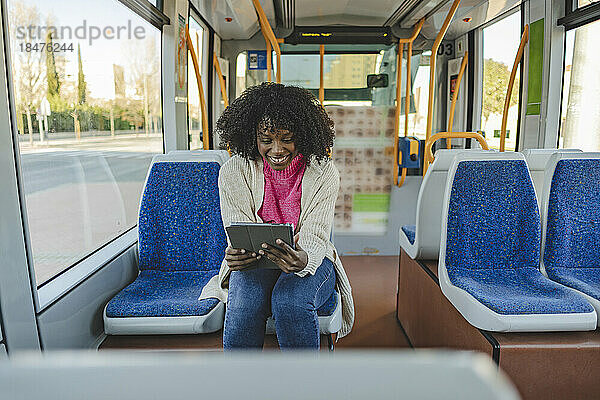 Glückliche Frau benutzt Tablet-PC in der Straßenbahn