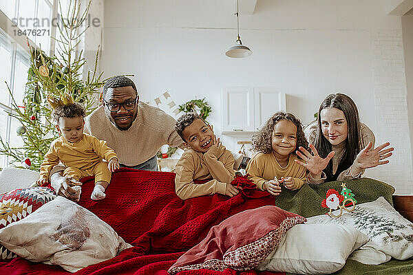 Glückliche Familie  die zu Weihnachten zusammen hinter dem Sofa steht