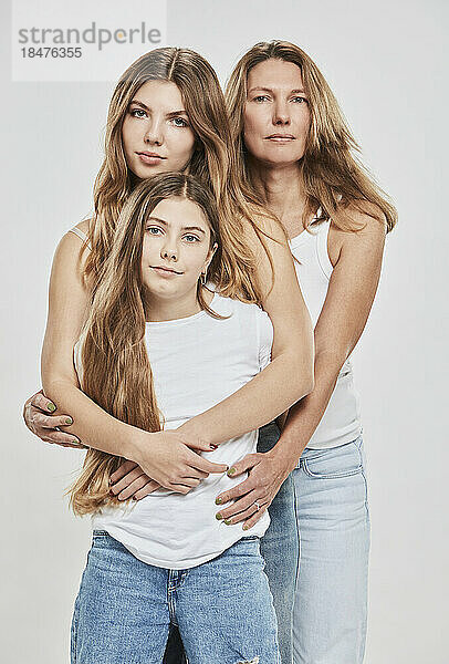 Mother and daughters together against white background