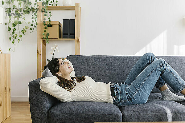 Junge Frau entspannt sich zu Hause auf dem Sofa