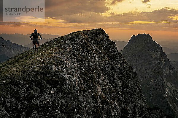 Mountainbiker fährt bei Sonnenuntergang auf den Gipfel