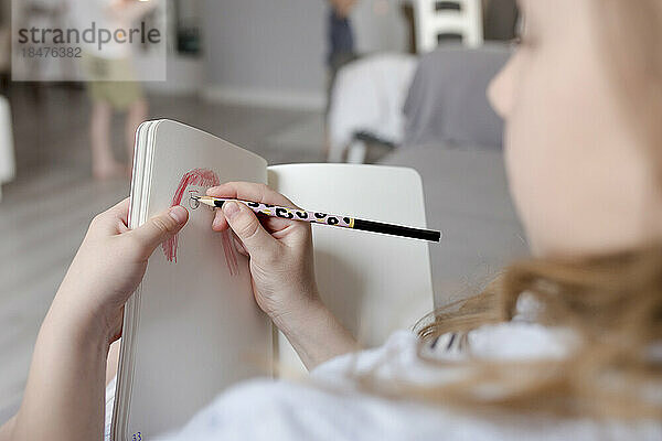Girl drawing in book at home