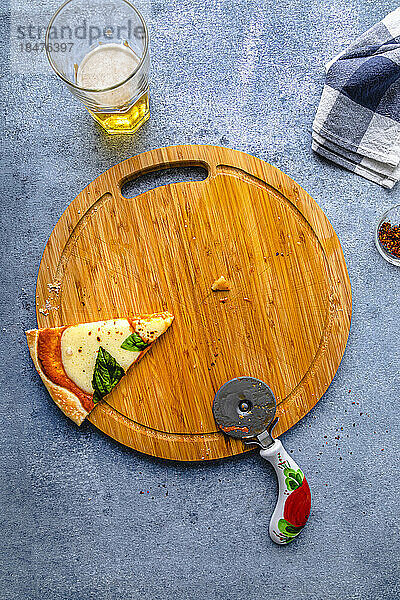 Slice of pizza with cutter kept on cutting board