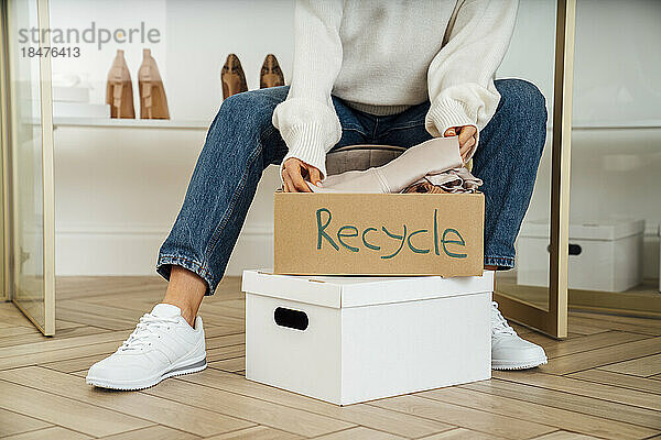 Junge Frau packt zu Hause Kartons mit Recycling-Kleidung