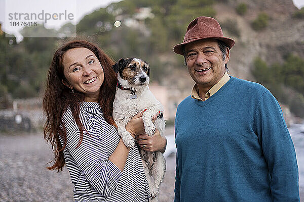 Happy couple with pet dog at beach