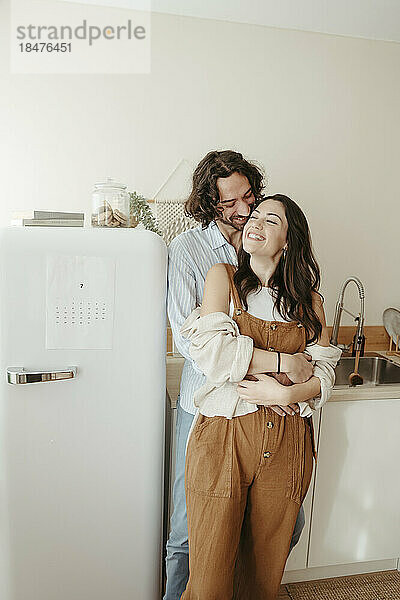Happy couple with arm around standing in kitchen