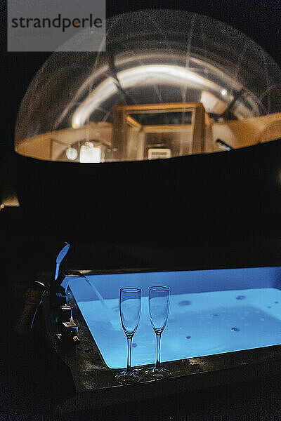 Empty champagne flutes on hot tub with dome tent in background