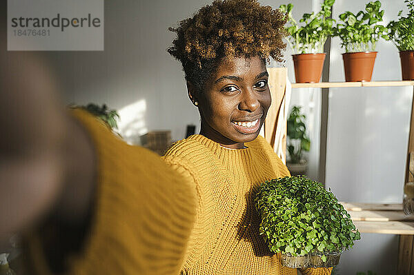 Lächelnde Frau  die zu Hause ein Selfie mit kleinem Gemüse macht