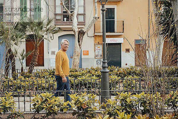 Älterer Mann geht inmitten von Pflanzen auf Fußweg