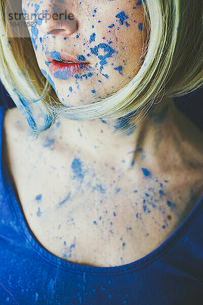 Das Gesicht einer Frau ist mit blauer Farbe bedeckt