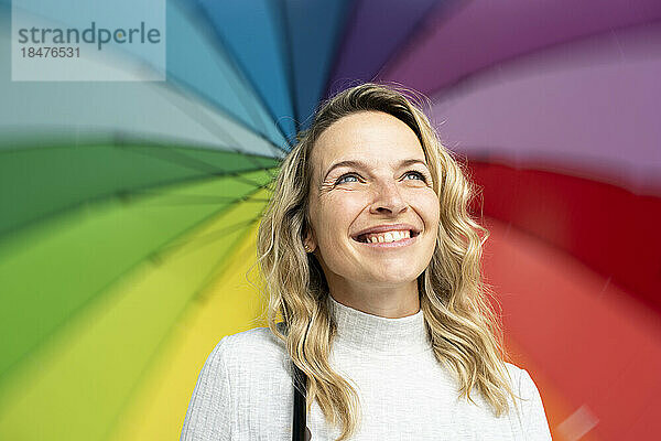 Blonde glückliche Frau mit buntem Regenschirm