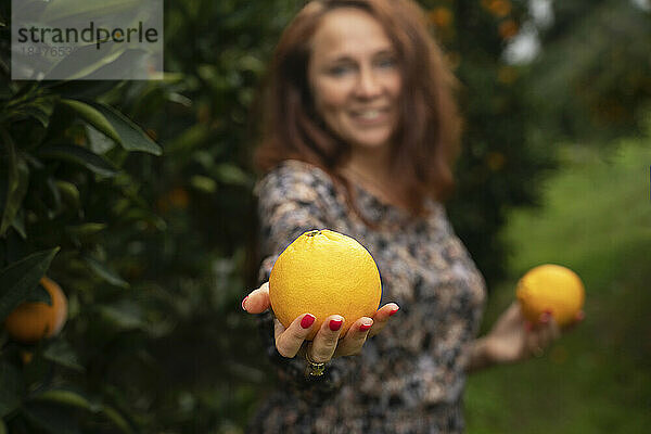 Reife Frau hält frische Orangen in der Hand
